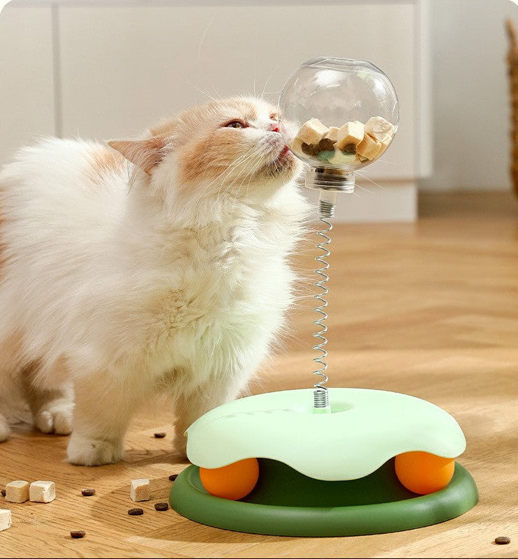 Cat playing with a transparent treat leakage ball toy on a wooden floor.